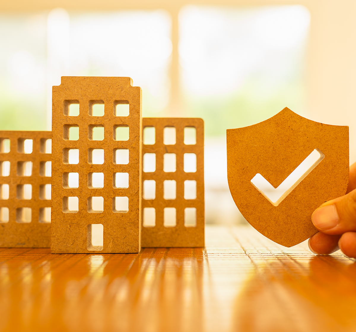 Buildings and shield with checkmark, wooden surface.